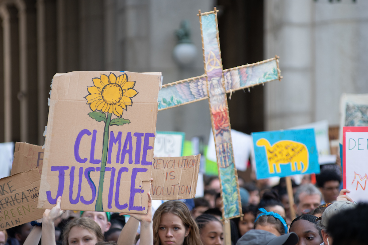 Kulkue, jossa nuoret kantavat mm. ristiä ja kylttiä, jossa lukee: Climate Justice.