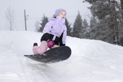 Sara Siikki lentää liukurinsa kanssa pulkkamäessä.